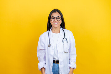 Young brunette doctor woman wearing stethoscope standing over isolated yellow background smiling with a happy and cool smile on face. showing teeth.