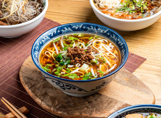 Taiwanese Noodle Soup topping with mince meat served in bowl with chopsticks and spoon isolated on wooden board side view of taiwan food