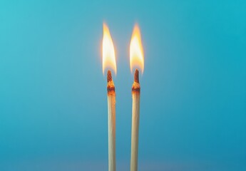 Close-up of Two Matchsticks with Flames on Blue Background, Capturing the Element of Fire, Ignition and Brightness in Still Life Photography