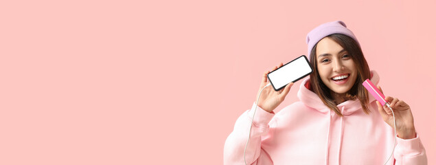 Young woman with phone and power bank on color background