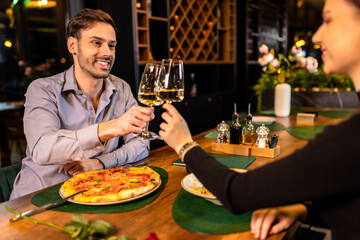 Hands of man and woman toasting with white wine in the restaurant.