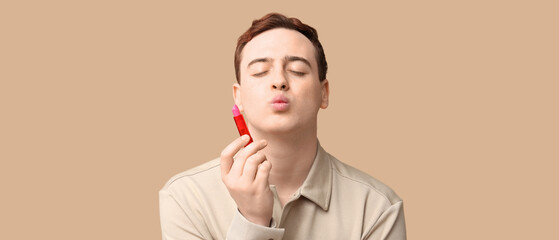 Handsome young man with lip balm on brown background