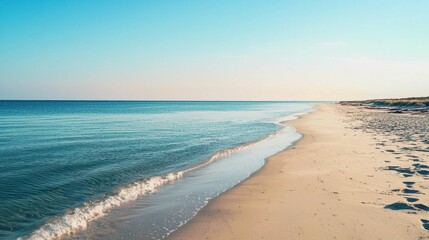 Obraz premium Tranquil Shoreline with Gentle Waves Under Clear Blue Sky