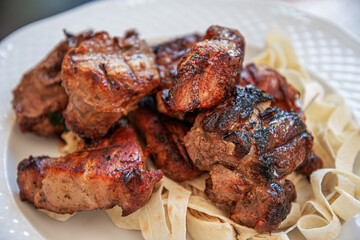 A plate of perfectly grilled meat with a crispy, smoky exterior and a tender, juicy interior rests on a bed of traditional flatbread.