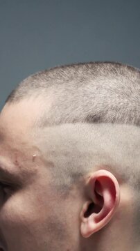 young guy cuts his hair and makes a short bald haircut. Master barber in a barbershop makes a haircut to a client close-up. Skinhead man of criminal appearance shaves his head with a machine
