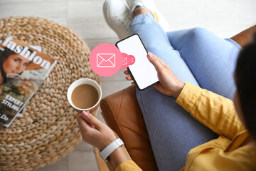 Woman holding mobile phone and cup of coffee in room