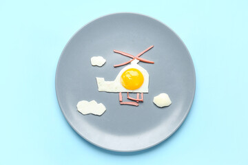 Plate with funny children's breakfast in shape of helicopter on blue background