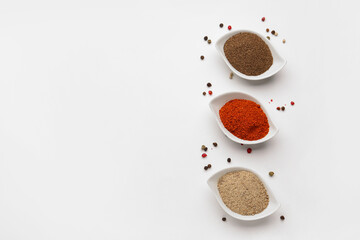 Bowls of spices and peppercorns on light background