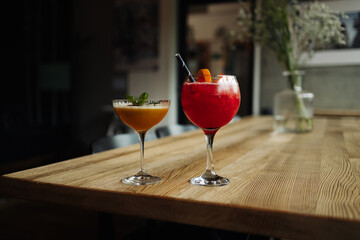 Two colorful summer cocktails in glasses on wooden table. Assortment of fresh summer drinks. Red sangria cocktails, orange punch cocktail. High quality photo