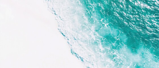 Serene teal waters meet a pristine white shore.  A breathtaking aerial view of ocean waves gently rolling in.