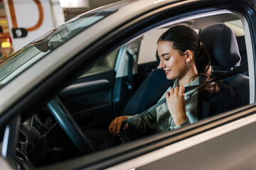Young businesswoman putting a seatbelt on. Ready to drive off from his parking spot in an underground garage.
