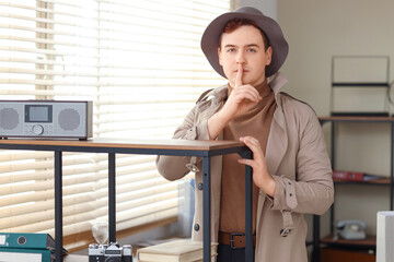 Male spy showing silence gesture in office