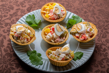 Salad with pineapples and tarts on a plate decorated with cilantro on a brown tablecloth.