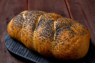 Traditional Jewish holiday challah with poppy seeds homemade on table on wooden board