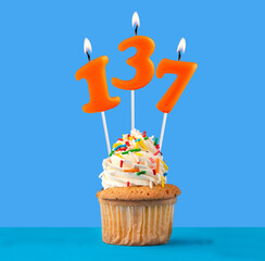 Orange candle number 137 - Birthday cupcake on blue background