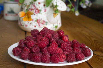 A pile of fresh raspberries on a plate. Fresh natural farm product. Summer mood.