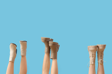 Female legs with different boots on blue background
