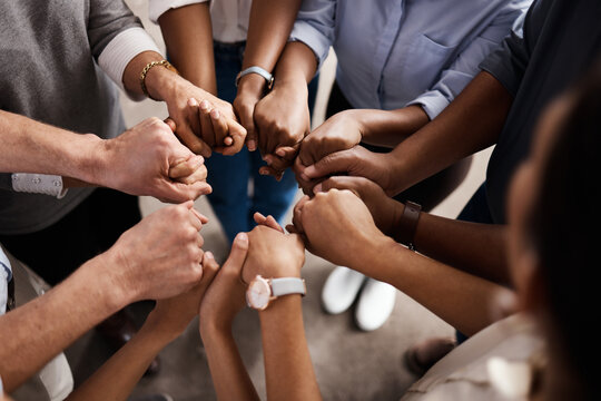 Above, business people and holding hands in circle for teamwork, diversity and synergy in office. Corporate community, collaboration and group in agency for inclusion, support and gesture for trust