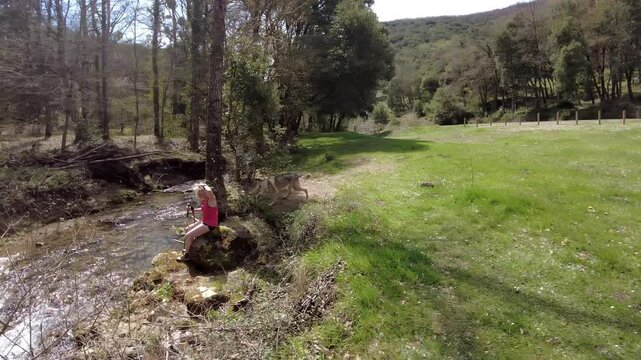 Czechoslovakian wolfdog running and sitting near river with woman hiker.