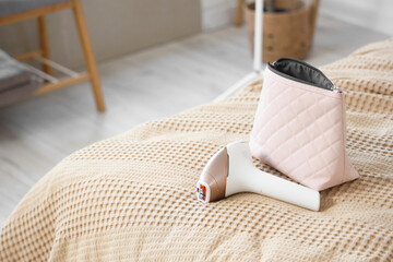 Modern photoepilator with bag on bed in room, closeup