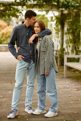 Fototapeta premium Young Cute Female Hugs Boyfriend. In Autumn Outdoor. Lovers Walking in Park. Attractive Funny Couple. Lovestory in Forest. Man and Woman. Cute Lovers in the Park. Family Concept. Happy Couple.