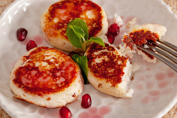 Fragrant fried tvorog pancakes with mint and pomegranate for the perfect breakfast.