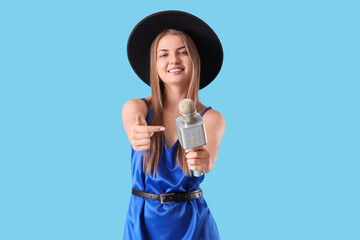 Beautiful woman with microphone singing karaoke on blue background