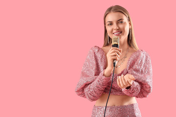 Beautiful woman with microphone singing karaoke on pink background
