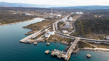 Spectacular aerial drone shot of the LNG (liquefied natural gas) terminal on Krk Island, Croatia, featuring a massive gas tanker docked at the facility