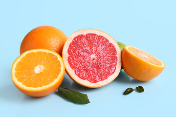 Different cut citrus fruits and leaves on blue background