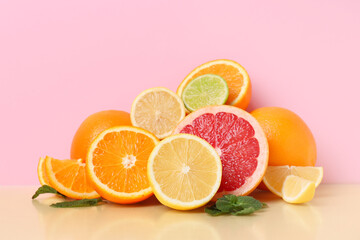 Different cut citrus fruits and mint leaves on color background