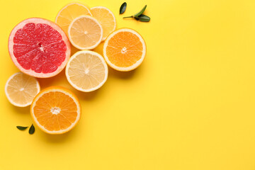 Different cut citrus fruits and leaves on yellow background