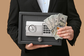 Businessman with dollar banknotes and safe on beige background, closeup