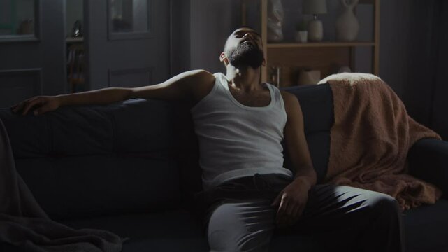 African American man lost in thoughts sits calmly on couch