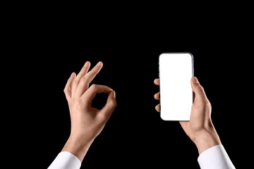 Man with blank mobile phone showing OK on black background