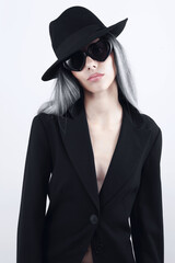 Fashion beautiful young woman with bleached long hair wearing sunglasses, black hat and black jacket, isolated on white background. For a magazine cover, advertising poster and web or shop banner