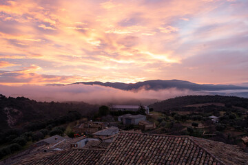 Sunrise in a village with tiled roofs and fog in an idyllic rural landscape
