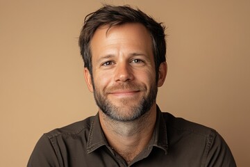 Fototapeta premium Smiling man in a casual shirt against a plain background during a portrait session capturing genuine emotion and warmth