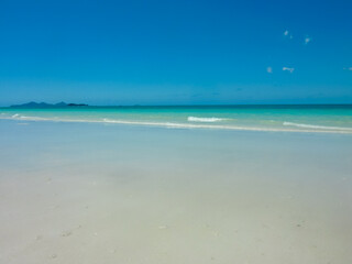 Fototapeta premium Pristine white sandy beach stretches along turquoise waters at Whitehaven Beach, Whitsunday Islands, Queensland, Australia. Gentle waves meet powdery silica sand. Vibrant blue sky. Summer vacation
