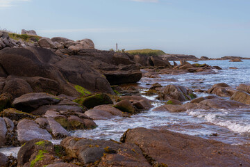 Felsige Küste mit einem Leuchtturm in Hintergrund in der Normandie.