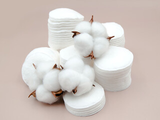Cotton flowers and stacks of cosmetic disks on a beige background