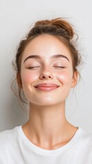 Naklejka premium Radiant Young Woman with Closed Eyes, Healthy Skin, and Messy Bun