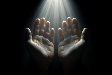 A pair of open hands, palms up in a prayerful or accepting gesture, against a dark background. A beam of light falls from above, illuminating the hands and creating a contrast between light and shadow