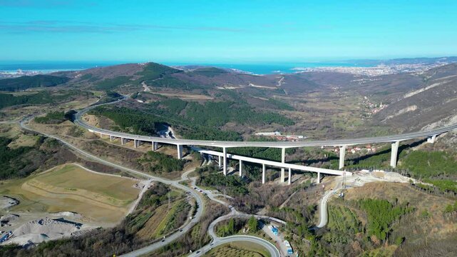 A stunning aerial drone view of Črni Kal, Slovenia, featuring the historic Castle of San Sergio atop a hill and the modern Črni Kal Viaduct, part of the A1 motorway (toll road), spanning Vipava Valley