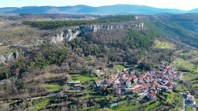 A stunning aerial drone view of Črni Kal, Slovenia, featuring the historic Castle of San Sergio atop a hill and the modern Črni Kal Viaduct, part of the A1 motorway (toll road), spanning Vipava Valley
