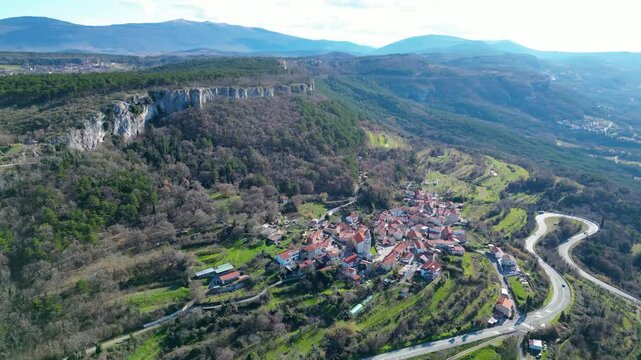 A stunning aerial drone view of Črni Kal, Slovenia, featuring the historic Castle of San Sergio atop a hill and the modern Črni Kal Viaduct, part of the A1 motorway (toll road), spanning Vipava Valley
