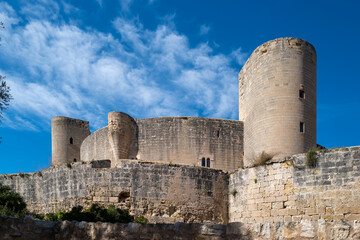 Naklejka premium A majestic medieval castle stands tall against a vibrant blue sky, its ancient stone walls and towers a testament to history.