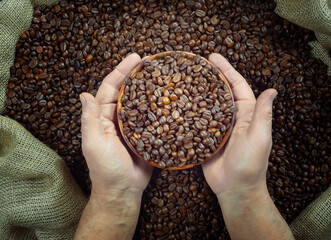 An elderly man stirs and pours roasted coffee beans in a bag. Close-up. Slow motion.