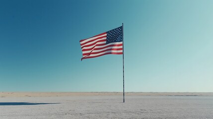 United States flag waving against a clear blue sky in open landscape on a calm day