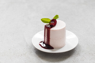 Cherry Cream pudding cylindrical shape. With cherry sauce. On a plate. Light gray background. Copy space